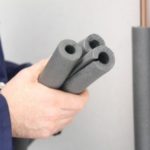 Person holding three pieces of pipe insulation material for winterizing plumbing systems.