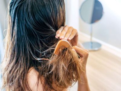 Woman combing wet hair, illustrating the benefits of softened water for improved hair health and hydration.