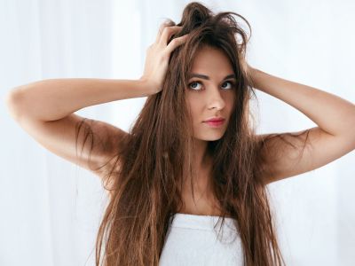 Woman with long, messy hair expressing frustration, illustrating effects of hard water on hair and skin.